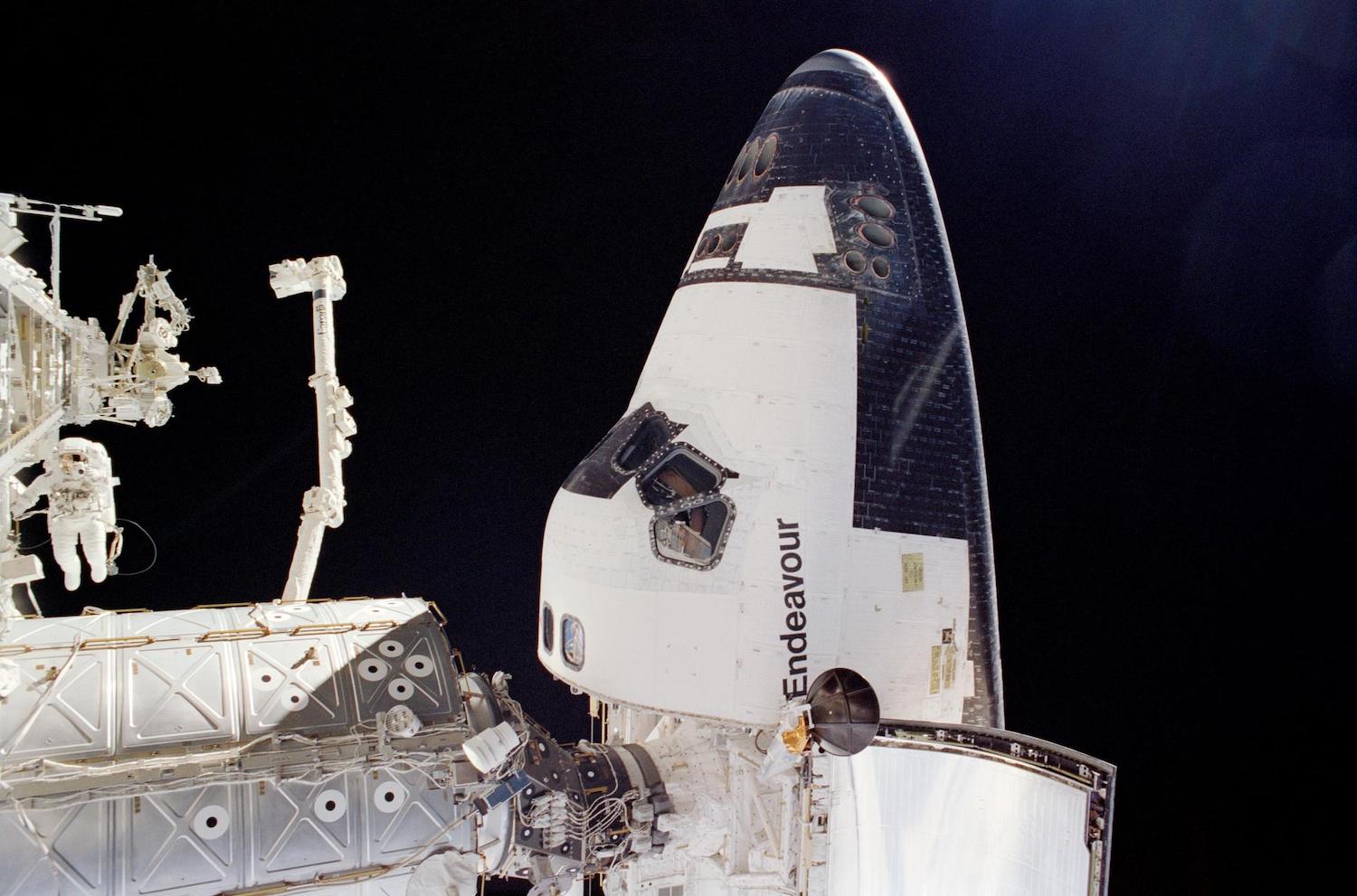 An astronaut conducts a spacewalk outside the Endeavour Space Shuttle.