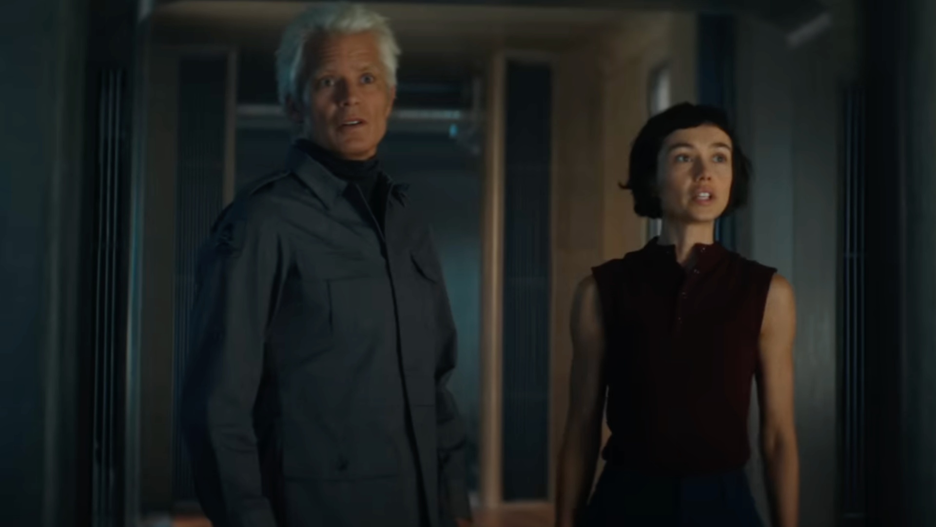 A man and woman stand next to each other and stare.